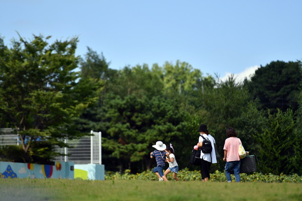 사진) 지난해 7월 수원시 탑동 시민농장을 찾은 시민과 아이들이 잔디밭에서 뛰어놀고 있다.ⓒ경기타임스
